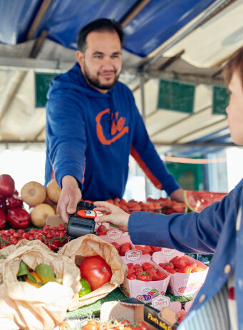 commerçant qui aide un enfant à choisir ses fruits et légumes