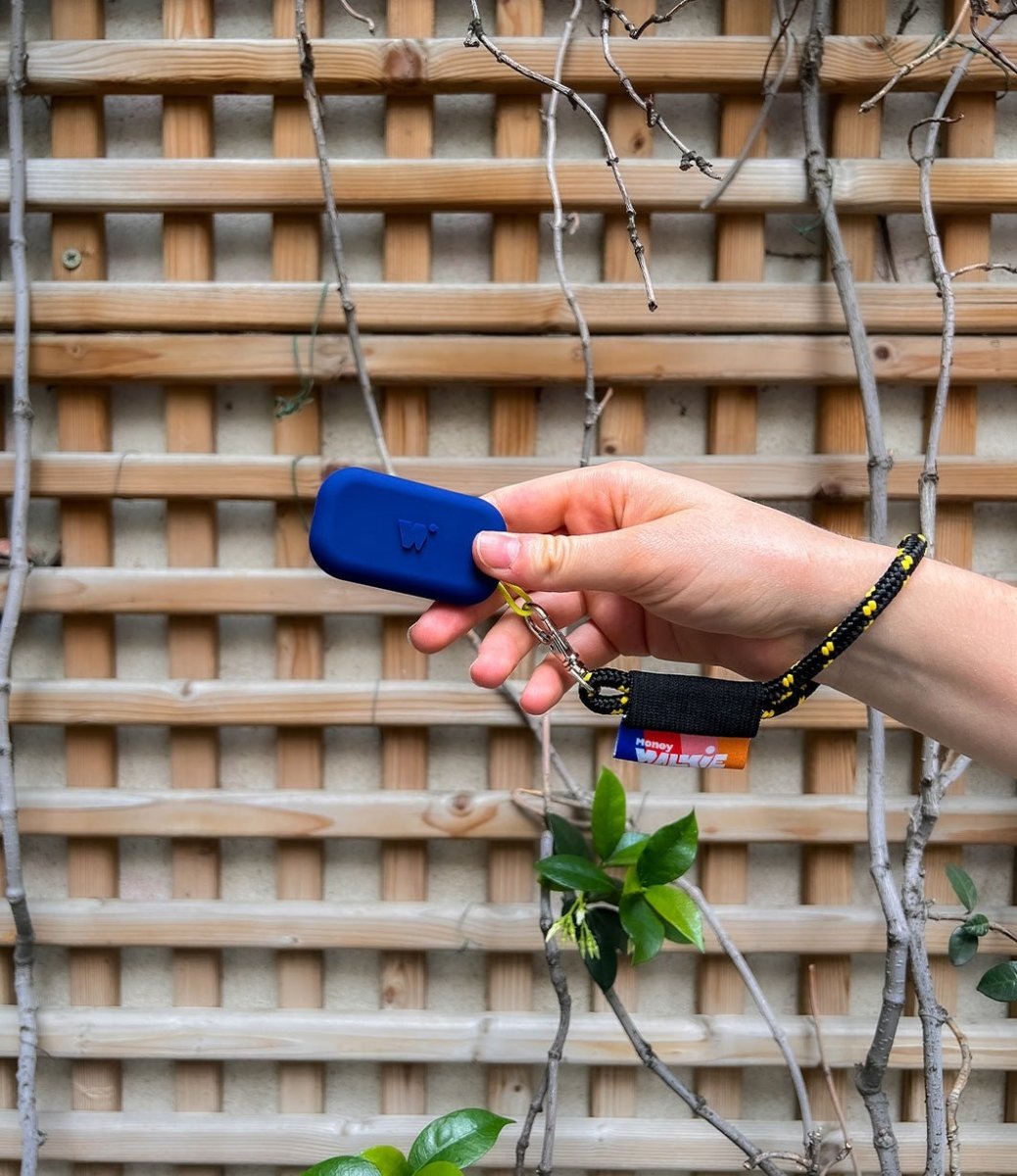 main qui tient un walkie bleu marine accroché à son porte-clés