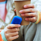 une adolescente qui tient un Walkie bleu électrique dans une main et une boisson chaude dans l'autre main