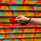 main qui tient un walkie rouge flash accroché à un porte-clés